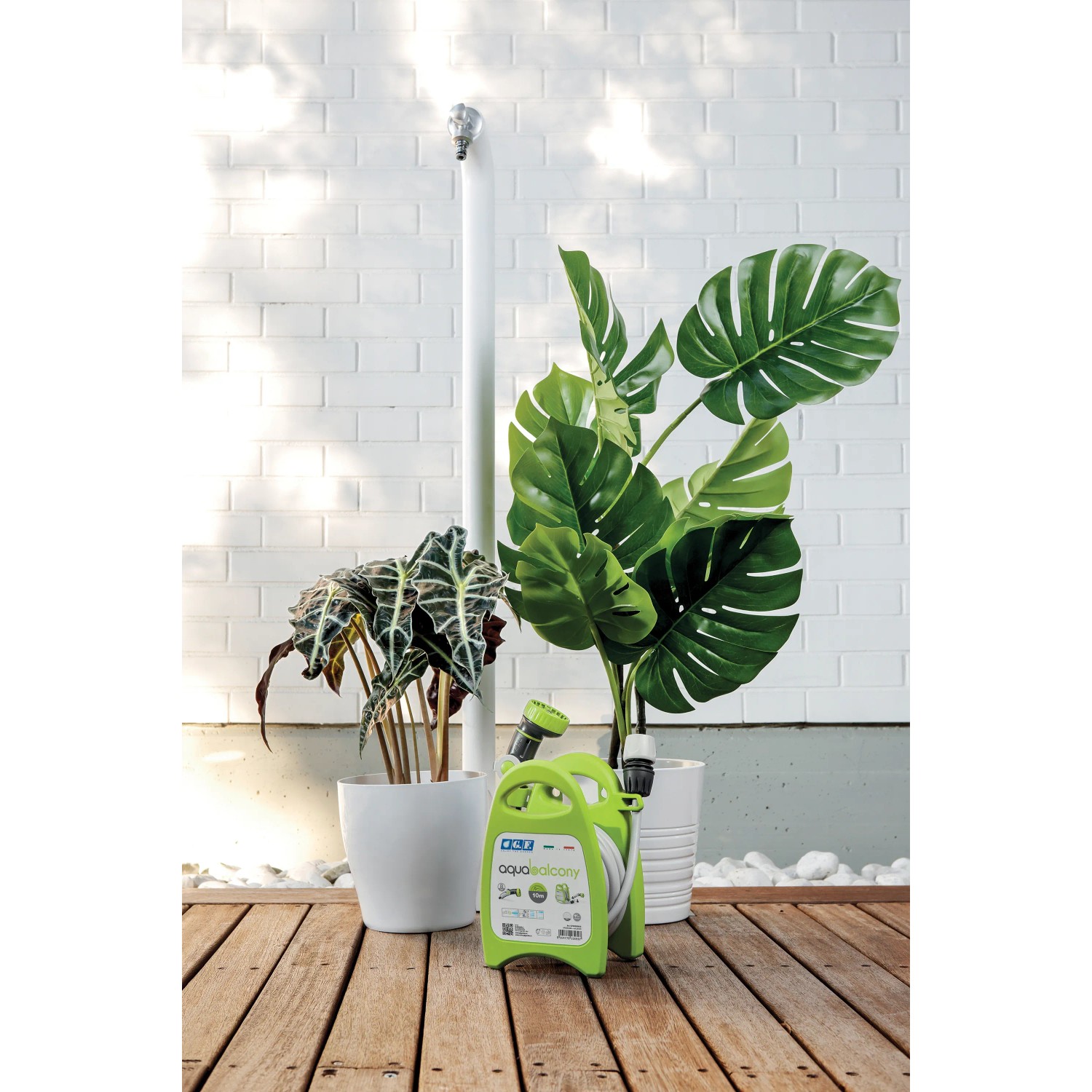 Avvolgitubo t.b.t. verde con tubo da giardino e lancia a spruzzo davanti alle piante. Irrigazione facilitata.