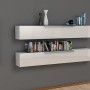 Mensole a muro bianche con libri e decorazioni su parete grigia.