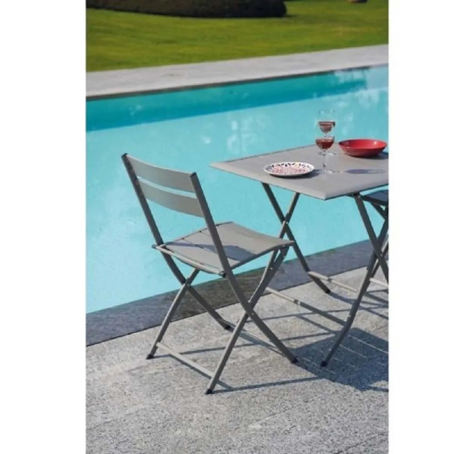 Tavolo da giardino grigio con sedia t.b.t. vicino alla piscina.