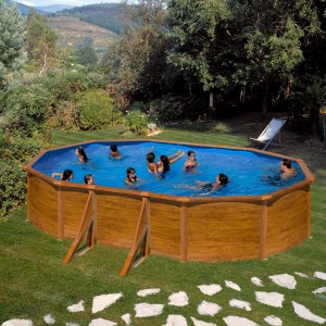Piscina ovale Gre Pool Pacific effetto legno, 610x375x120 cm, piena di persone in giardino.