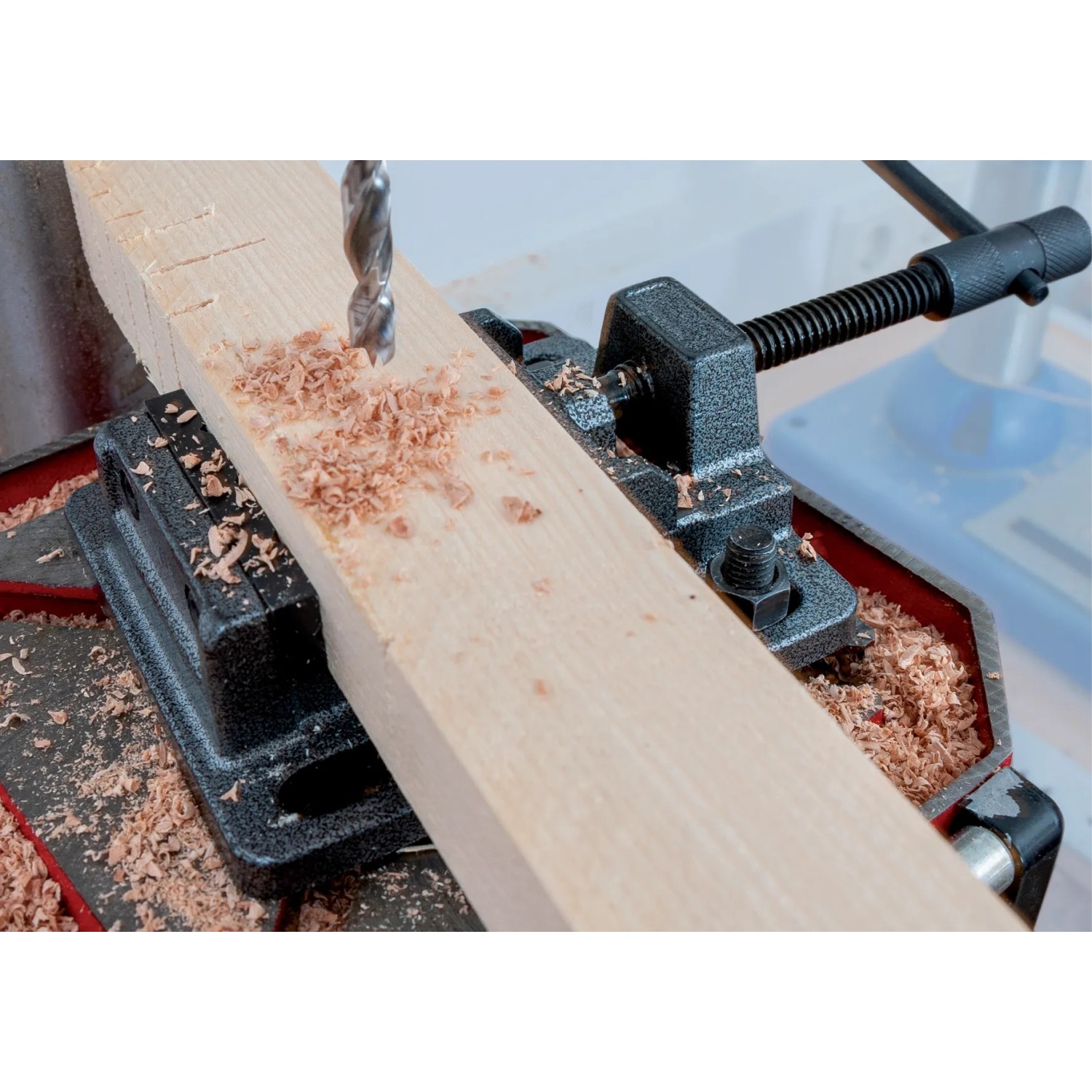 Dettaglio di un trapano a colonna t.b.t. che fora un pezzo di legno.