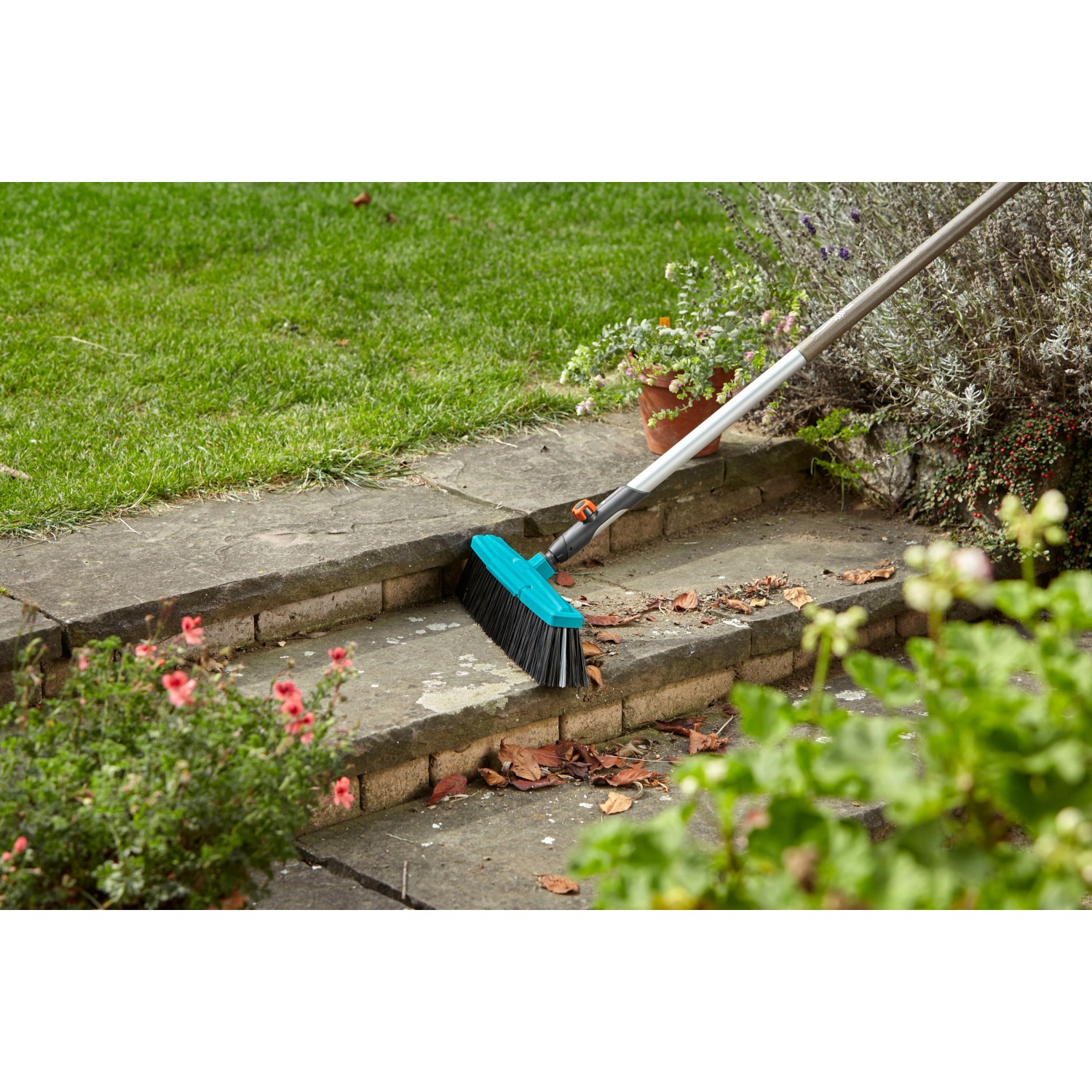 Scopa stradale Gardena Combisystem con bordo raschiante per rimuovere sporco e foglie su gradini in pietra.