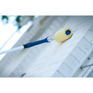 Rullo per facciate LUX 25 cm con manico telescopico mentre dipinge un muro.