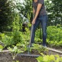 Donna che usa un rastrello da giardino per lisciare il terreno in un'aiuola.