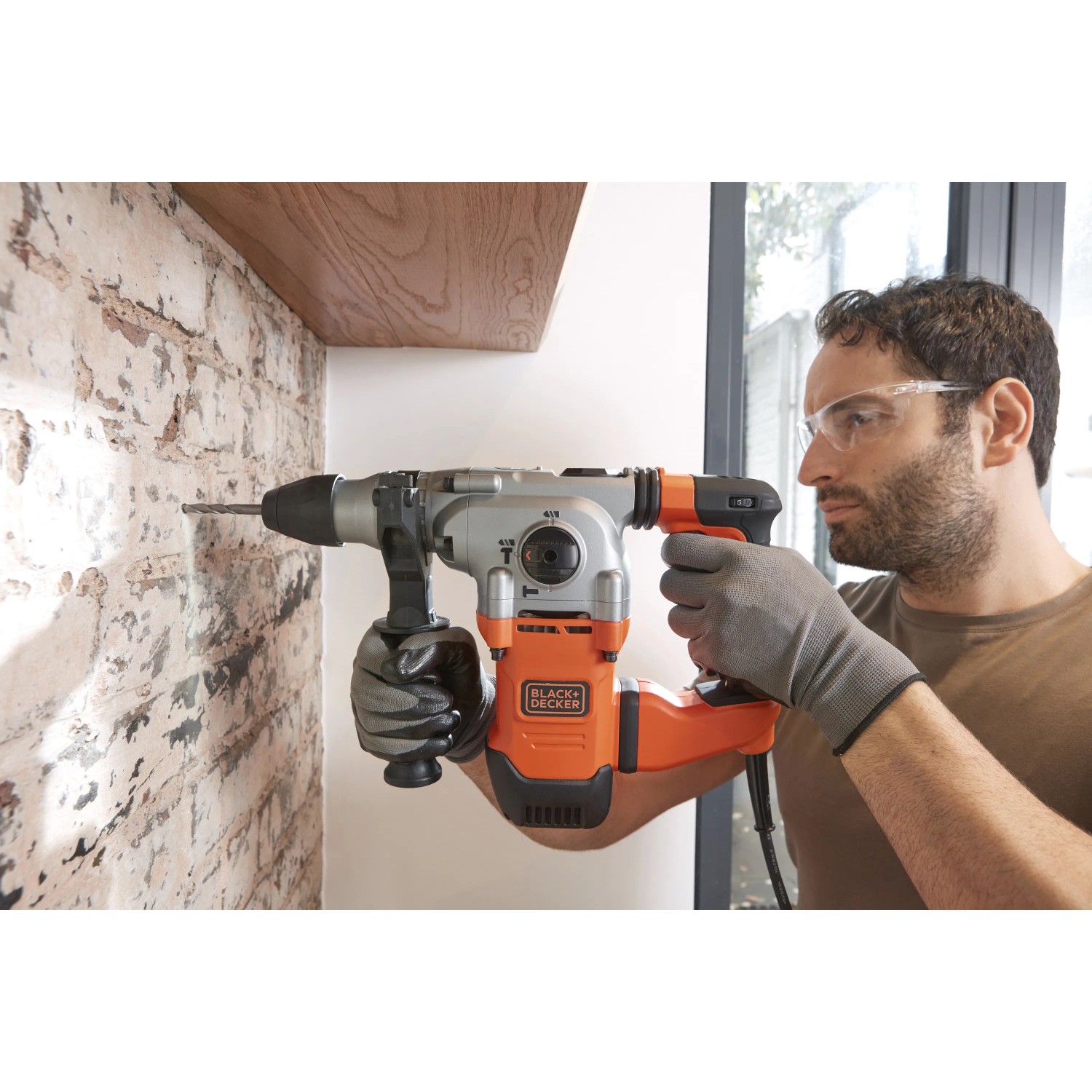 Trapano a percussione Black+Decker BEHS03K (1250 W) mentre fora un muro.