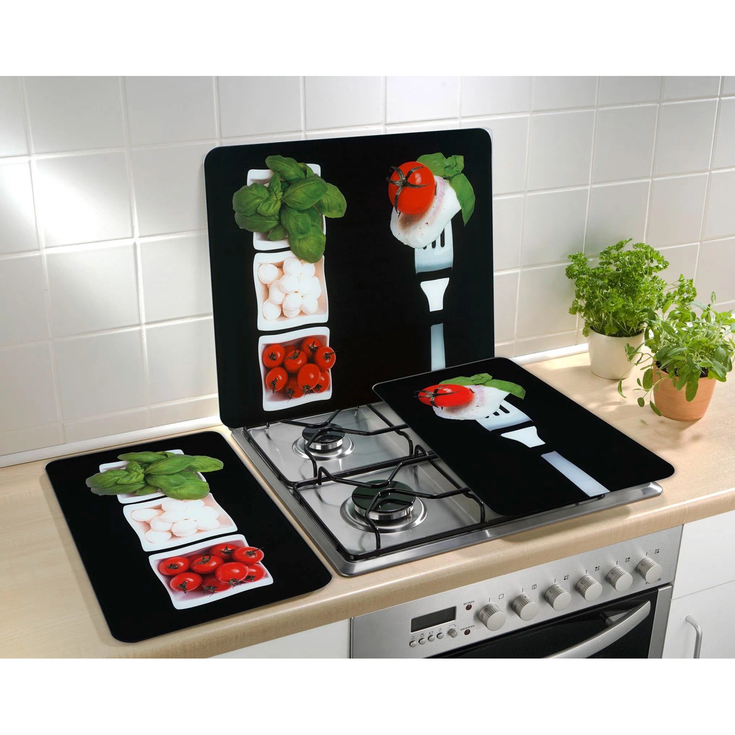 Set di 2 coperture per piano cottura Wenko Caprese su un fornello, con motivi di pomodori, mozzarella e basilico.