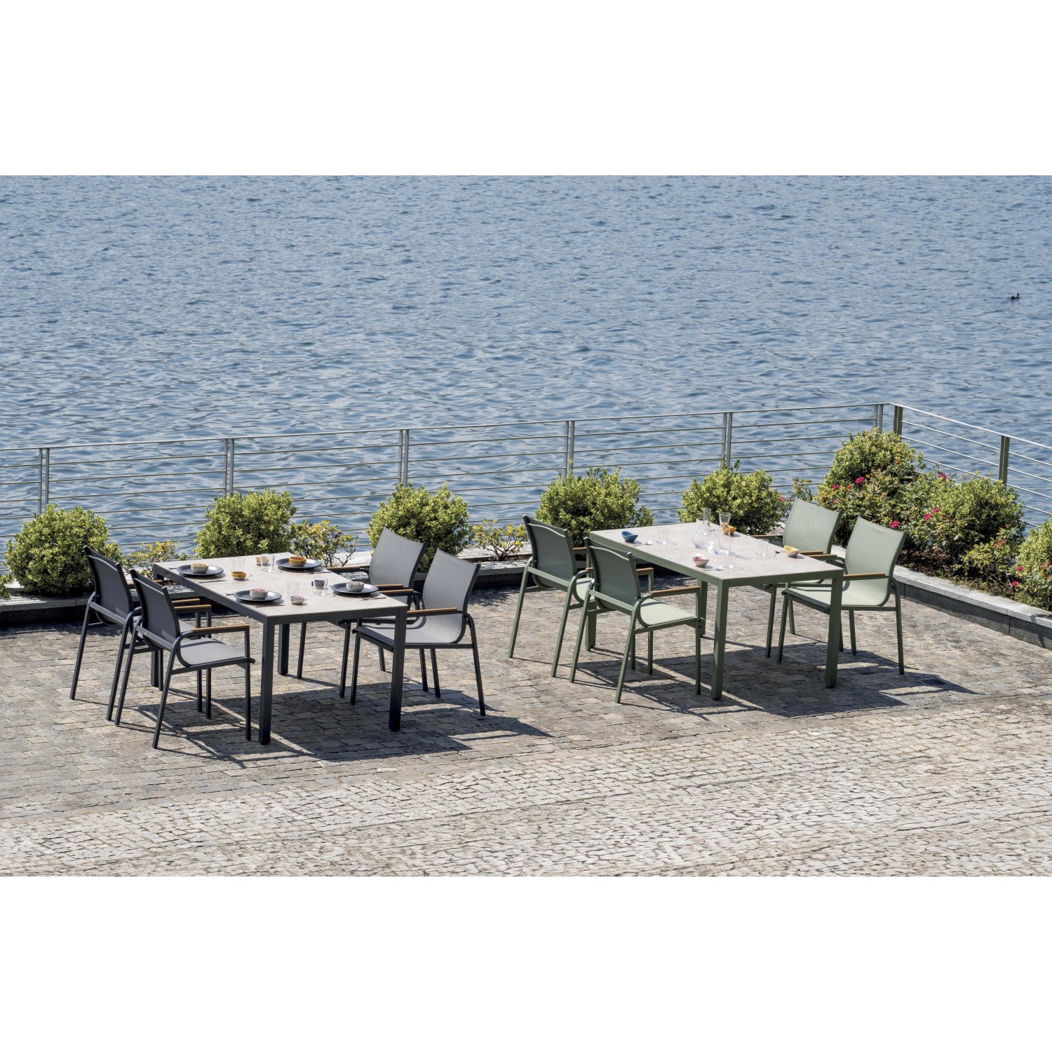Due set di mobili da giardino t.b.t. con tavoli e sedie su una terrazza sul lago.