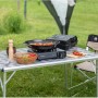 Fornello da tavolo Campingaz Camp'Bistro 3 con accessori su un tavolo da campeggio all'aperto.