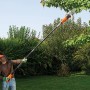 Uomo che usa il potatore elettrico Black+Decker per tagliare rami in giardino.