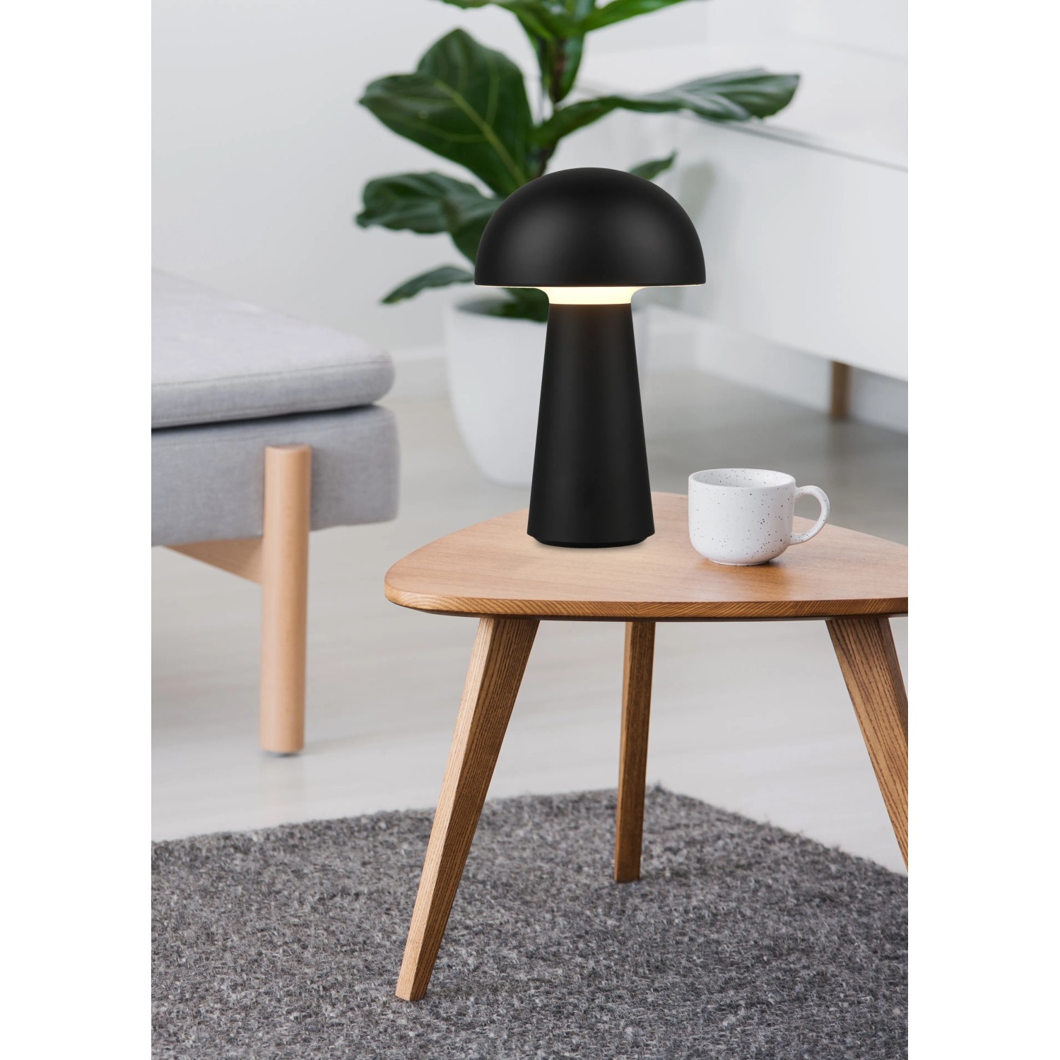 Lampada da tavolo a LED Reality Lennon nera, Ø 13,6 cm, design a fungo su un tavolo.