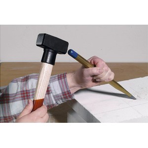 Un uomo usa una mazzetta LUX (800g) e uno scalpello per lavorare la pietra.