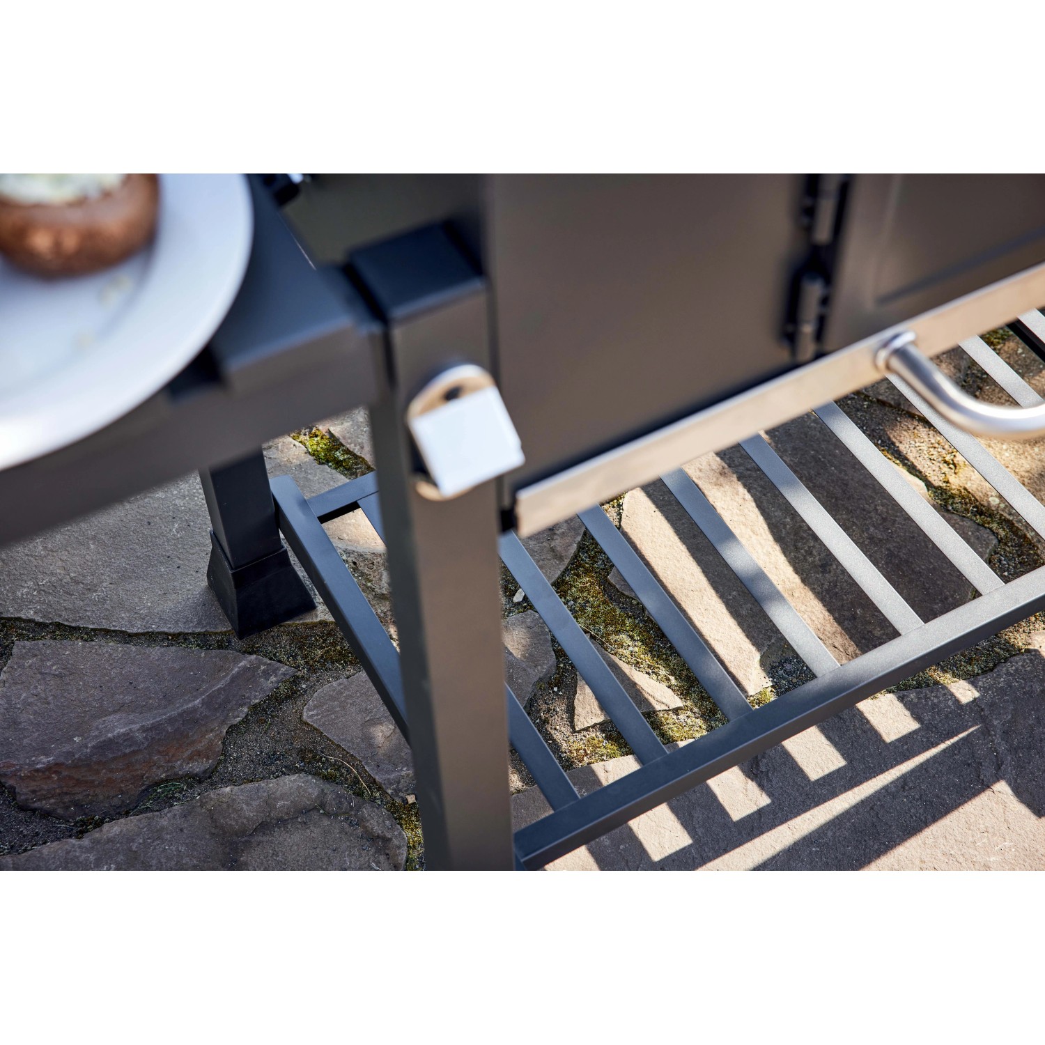 Dettaglio di un barbecue a carbonella con ripiano e griglia.