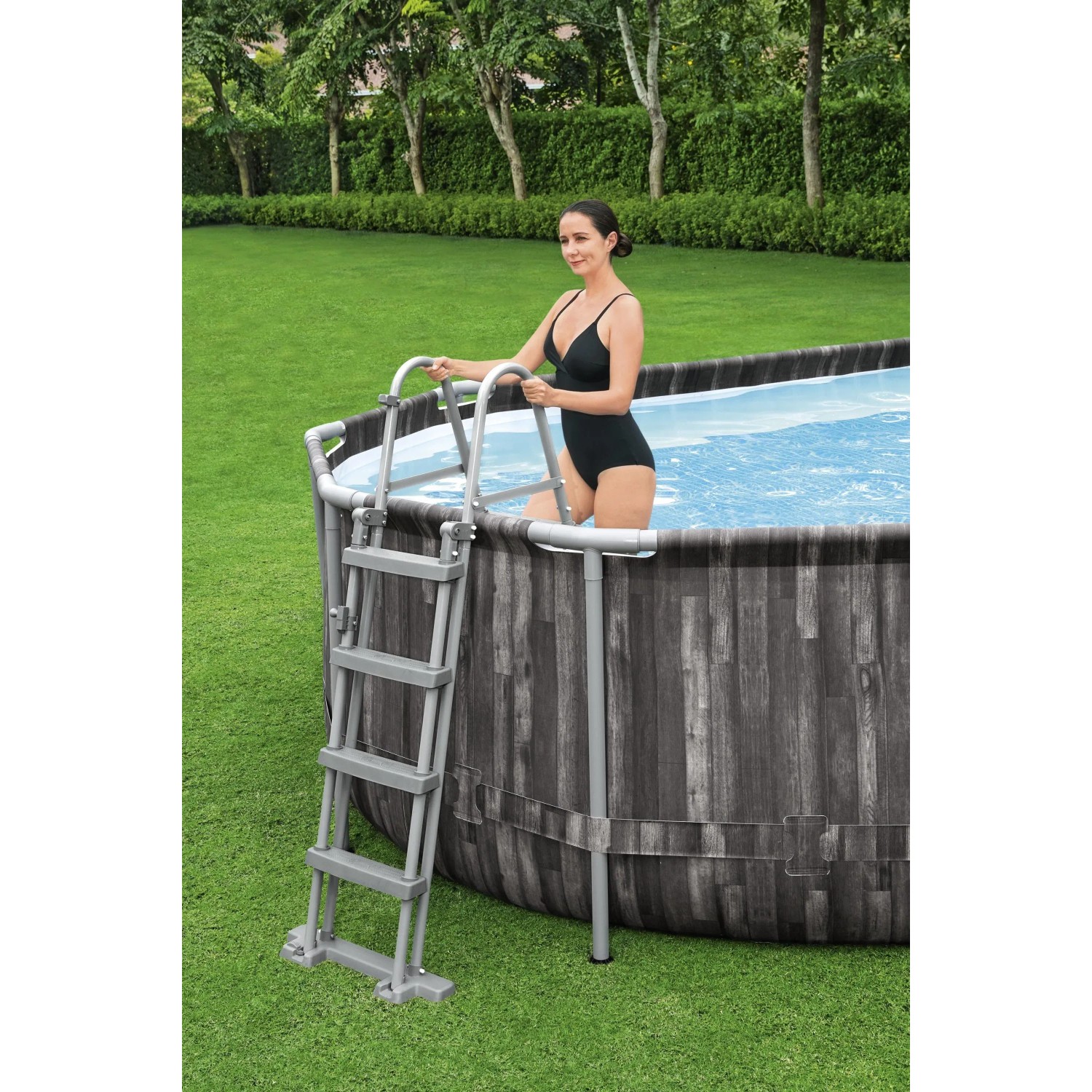 Piscina fuori terra ovale effetto legno con scaletta. Donna che entra in piscina.