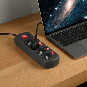 Multipresa t.b.t. grigia con interruttori e laptop su un tavolo.