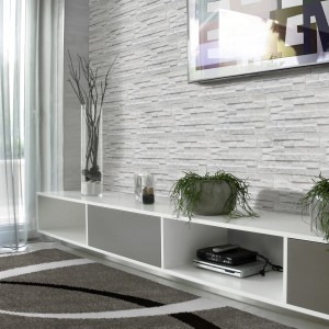 Soggiorno con piastrelle da rivestimento t.b.t. effetto pietra e mobile TV moderno.