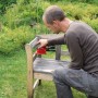 Levigatrice multifunzione Einhell TH-OS 1016 mentre leviga una panca di legno in giardino.