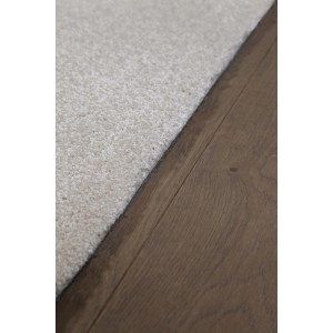 Dettaglio: Tappeto a pelo corto beige t.b.t. su pavimento in legno.