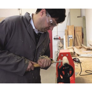 Uomo che lavora il legno con lo scalpello da tornio Einhell su un tornio.