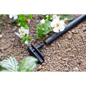 Connettore nero t.b.t. per sistema di microirrigazione, primo piano in giardino.