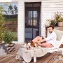 Zanzariera magnetica tesa antracite su porta patio, uomo e cane si rilassano sul lettino.