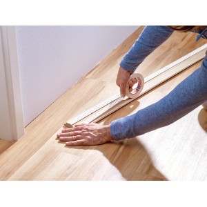 Applicazione del nastro di montaggio Tesa per carta da parati e intonaco su una striscia di legno.