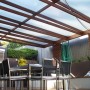 Patio con lastre di plastica trasparenti e telaio in legno come copertura.
