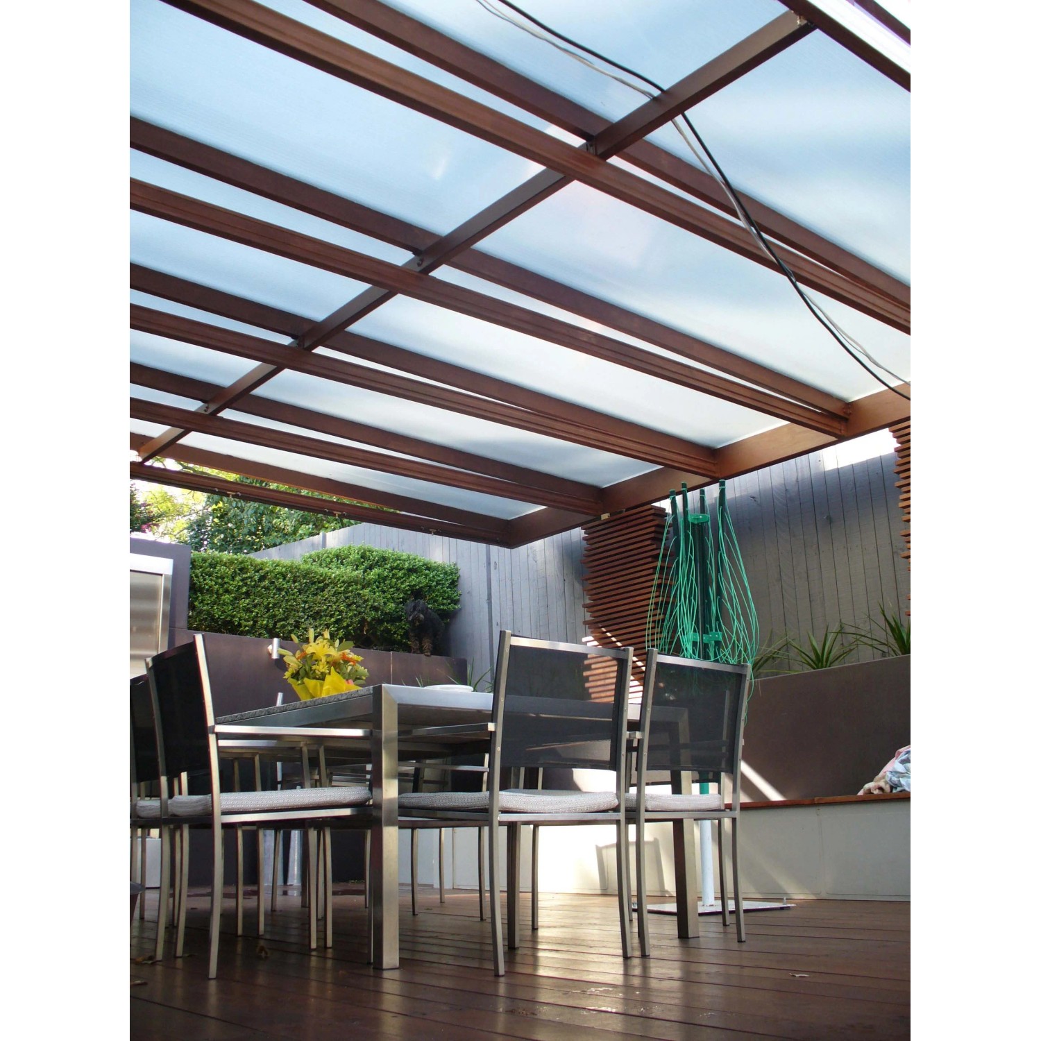 Patio con lastre di plastica trasparenti e telaio in legno come copertura.