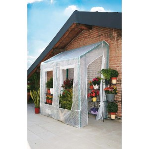 Piccola serra t.b.t. con piante davanti a un muro di mattoni.