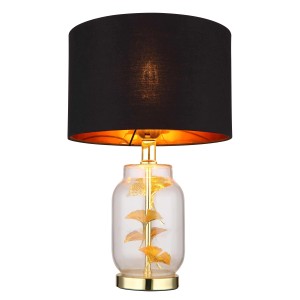 Elegante lampada da tavolo con paralume nero e foglia di ginkgo dorata nella base in vetro.