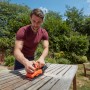 Uomo che leviga un tavolo con levigatrice orbitale Black+Decker BEW220. Levigatrice in arancione e nero.