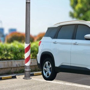 Palo con protezione rosso-bianca accanto a un'auto parcheggiata.