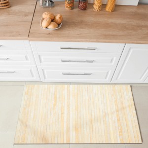 Tappeto da cucina/zerbino chiaro a righe davanti a mobili da cucina bianchi.