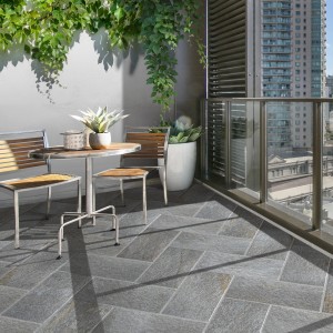 Terrazza con piastrelle per esterno t.b.t. grigie a spina di pesce e area salotto.