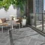Terrazza con piastrelle per esterno t.b.t. grigie a spina di pesce e area salotto.