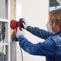 Uomo che leviga telaio finestra con levigatrice rotorbitale Einhell TC-RS 425 E rossa.