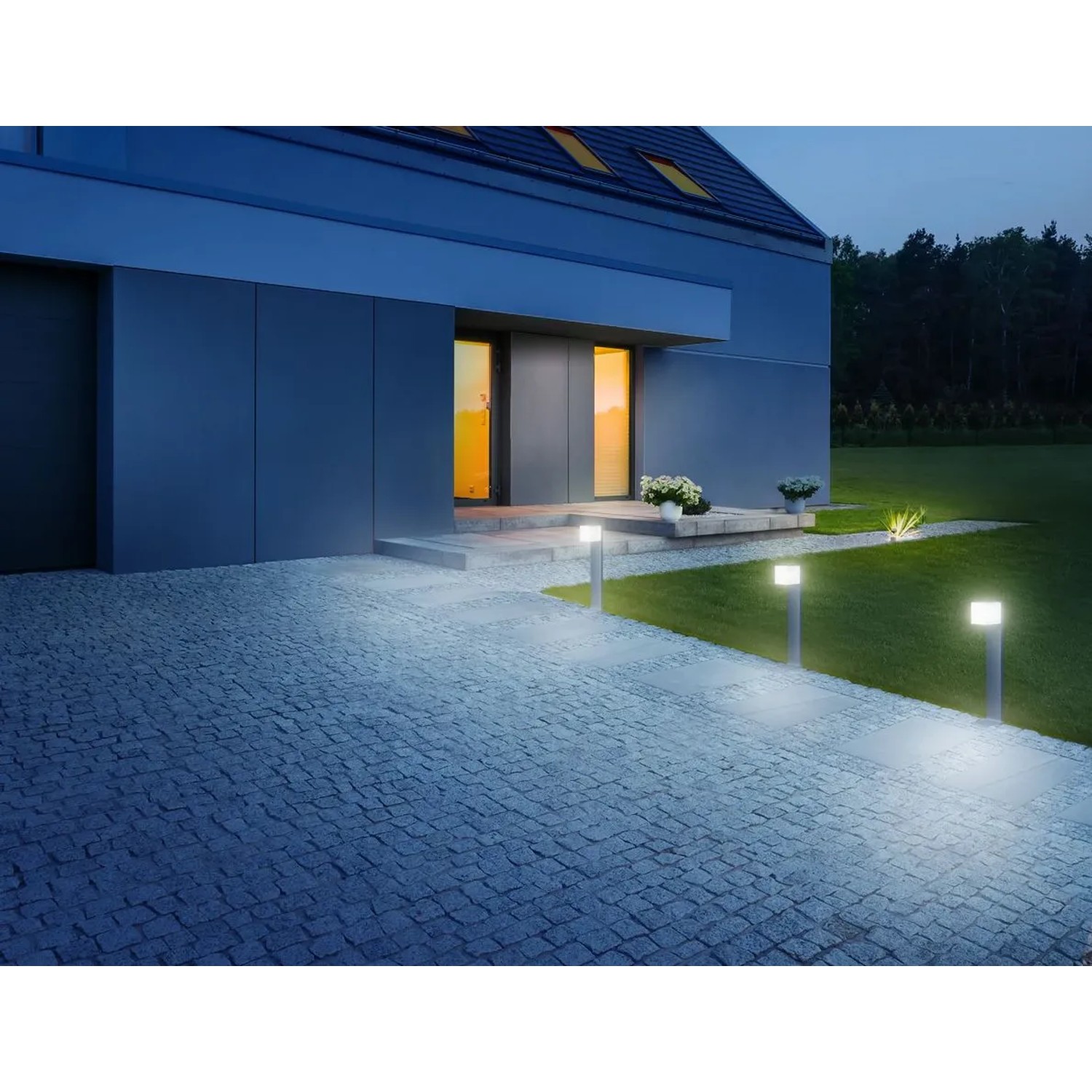 Lampada da giardino Steinel LED Bluetooth GL 80 antracite illuminata lungo un vialetto pavimentato.