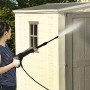 Donna pulisce casetta da giardino in plastica Keter (3,39 m²) con idropulitrice.
