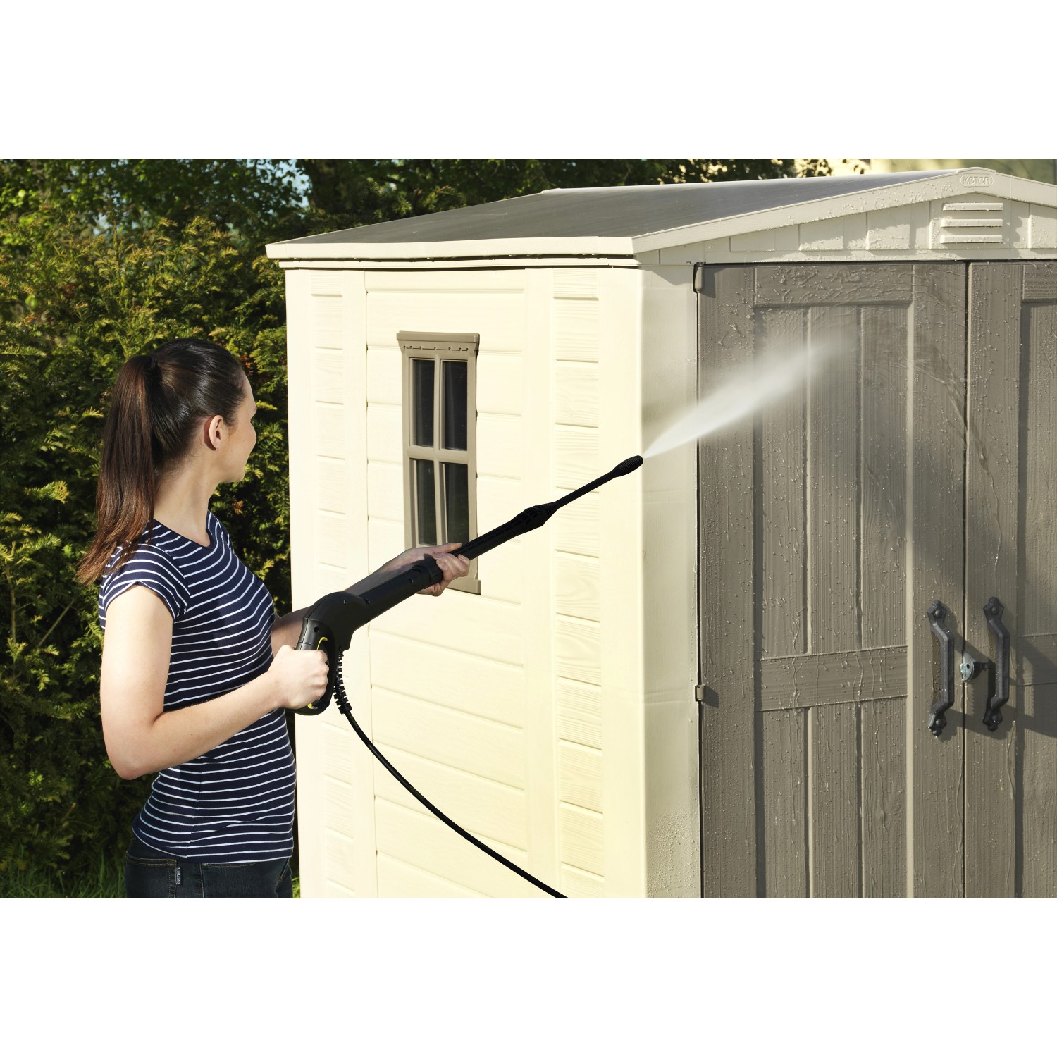 Donna pulisce casetta da giardino in plastica Keter (3,39 m²) con idropulitrice.