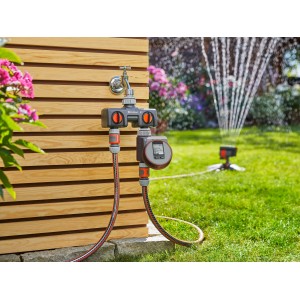 Distributore a 2 vie Gardena con timer collegato al rubinetto e irrigatore da giardino.