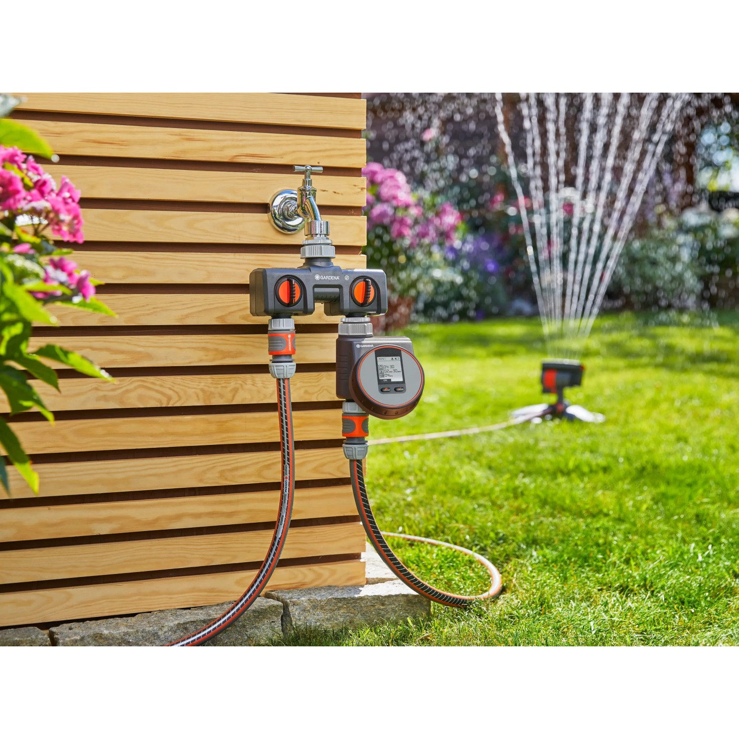 Distributore a 2 vie Gardena con timer collegato al rubinetto e irrigatore da giardino.
