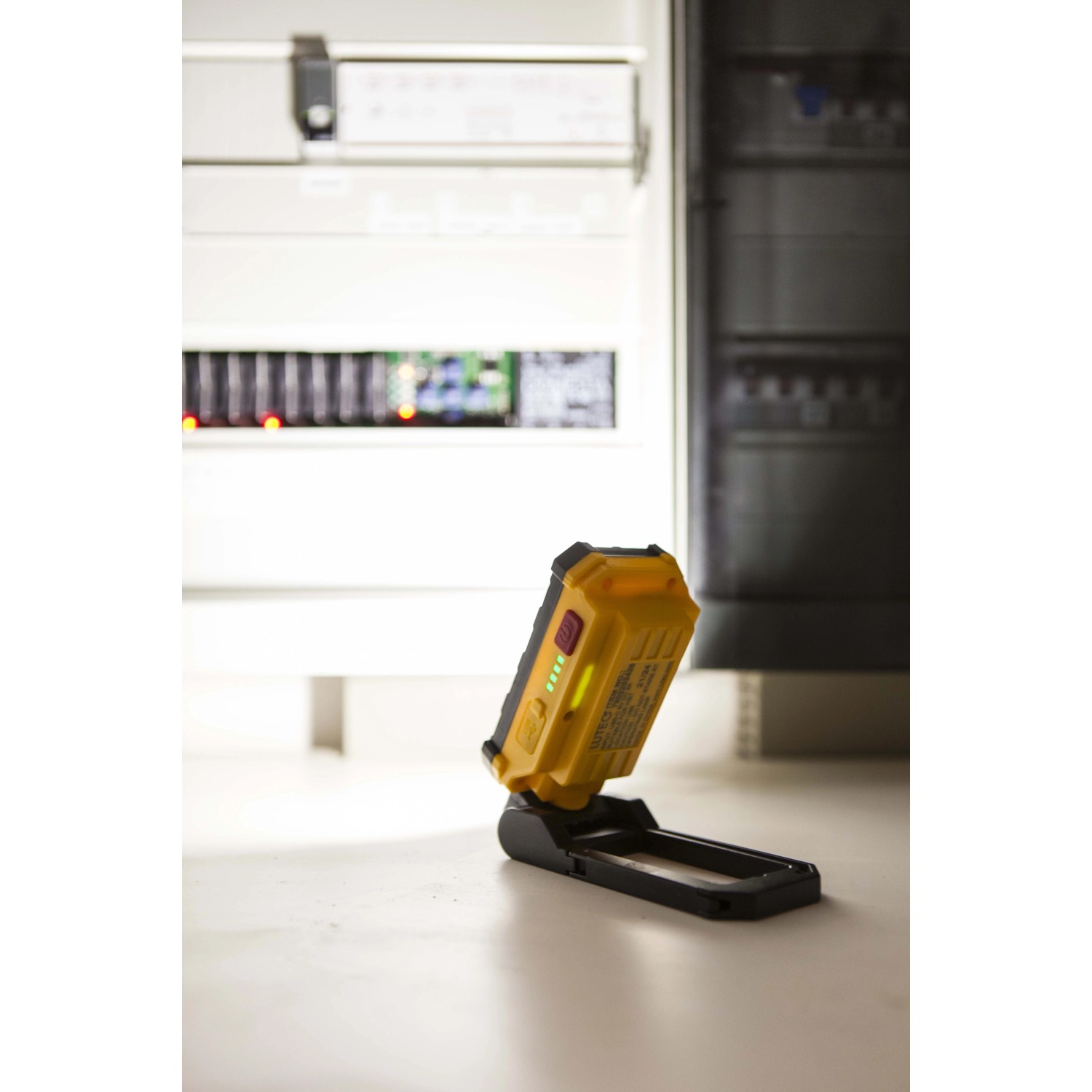 Faro LED da esterno t.b.t. giallo con batteria e indicatore di carica davanti al quadro elettrico.