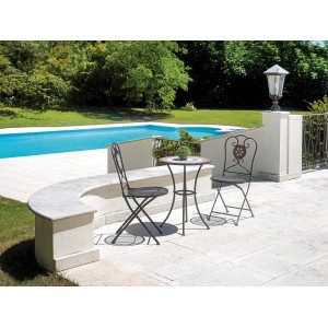 Set da giardino con due sedie e tavolo su una terrazza a bordo piscina.