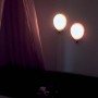 Due lampade LED da terra a forma di palloncino su una parete accanto a un letto.