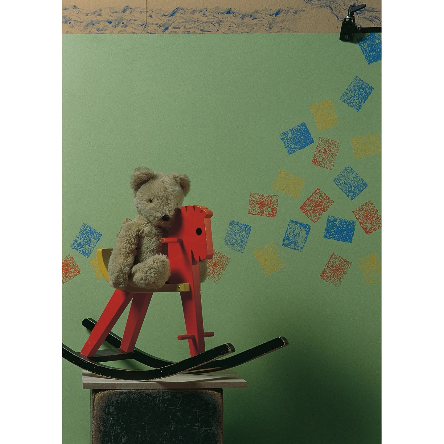 Decorazione murale con spugna effetto LUX: quadrati colorati su parete verde, orsacchiotto su cavallo a dondolo.