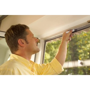 Uomo che fissa una zanzariera bianca Tesa con velcro a una porta.