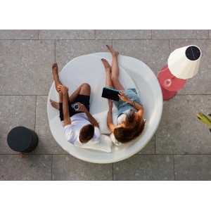 Coppia si rilassa su divano da esterno rotondo bianco con illuminazione esterna t.b.t. sullo sfondo.