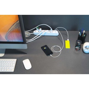 Ciabatta t.b.t. collegata con smartphone e power bank su una scrivania.