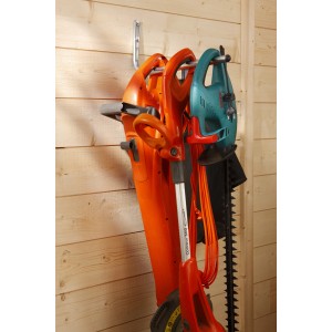 Gancio a muro con attrezzi da giardino: soffiatore, tagliaerba e tagliasiepi su parete in legno.