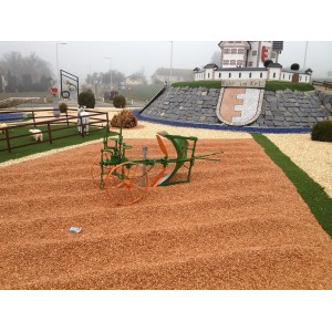 Area decorativa con t.b.t. ed erpice storico di fronte a scenario di villaggio in miniatura.