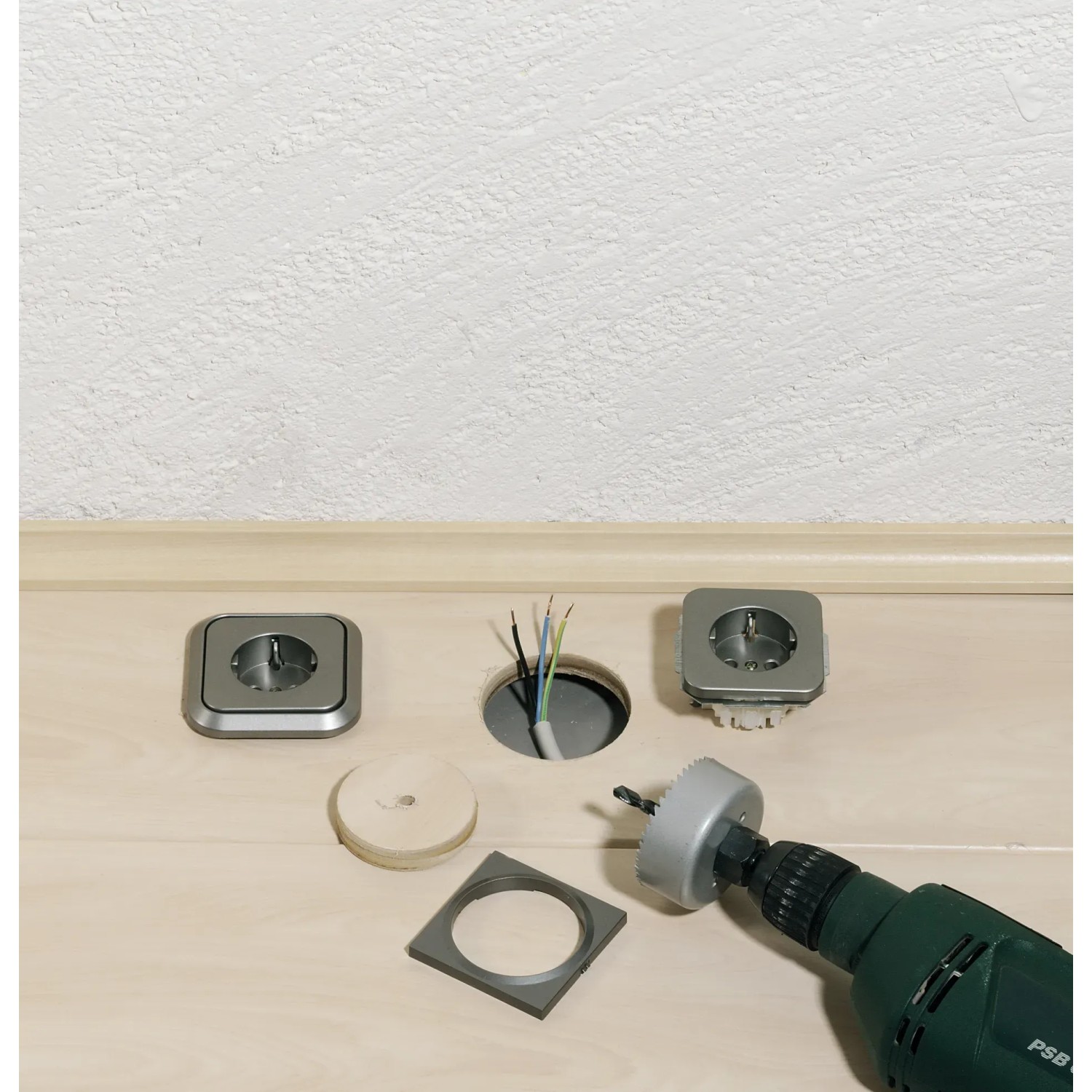 Set di seghe a tazza LUX (4 pezzi) in uso per forare una presa in legno.